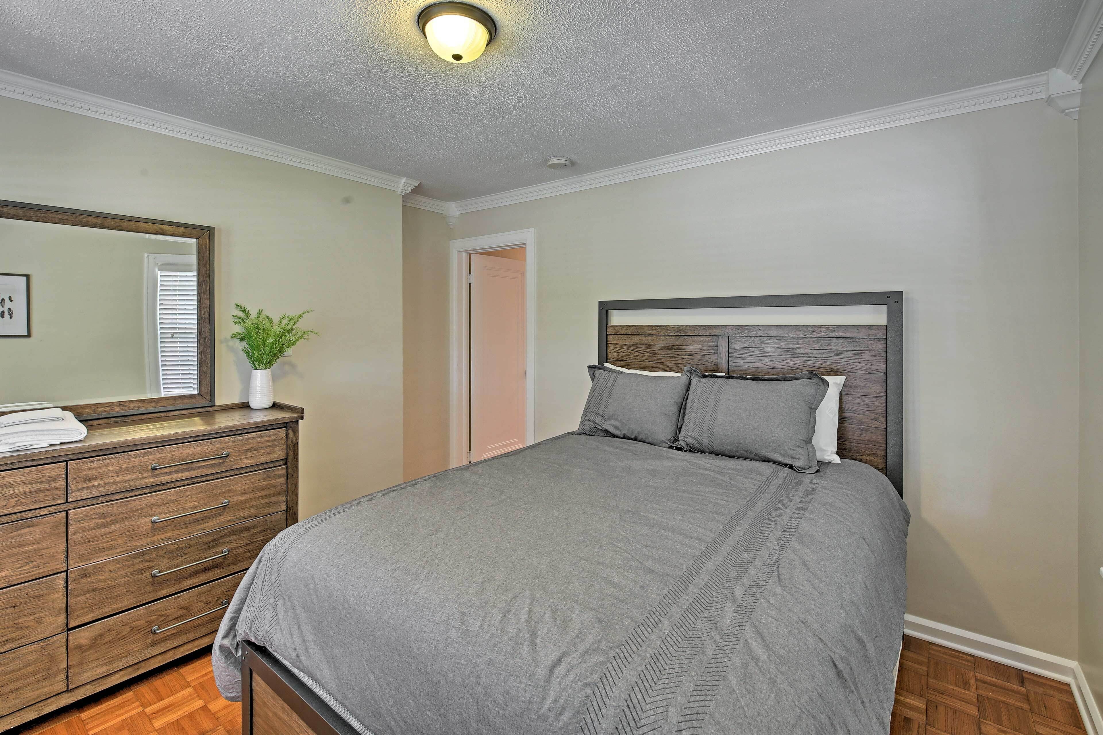 Een slaapkamer met een bed, een dressoir, een spiegel en een plant.
