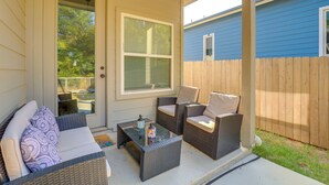 A covered patio with wicker furniture, a glass table, and a door leading to a backyard. - Modern Family Home Near At&t Stadium & More! (Mansfield)
