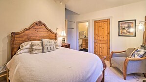 A bedroom with a wooden headboard, a large bed, a chair, a wooden wardrobe, and a framed picture on the wall. - Ketchum Couple's Retreat: 1 Mi to Sun Valley! (Ketchum)