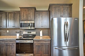 A kitchen with dark wooden cabinets, stainless steel appliances, and a granite countertop.