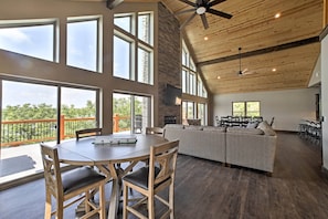 A spacious room with a large dining table, wooden chairs, a sofa, and a ceiling fan.