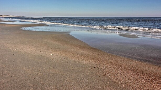 A beach with wet sand and gentle waves.