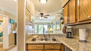 A kitchen with wooden cabinets, a double sink, and a coffee maker.