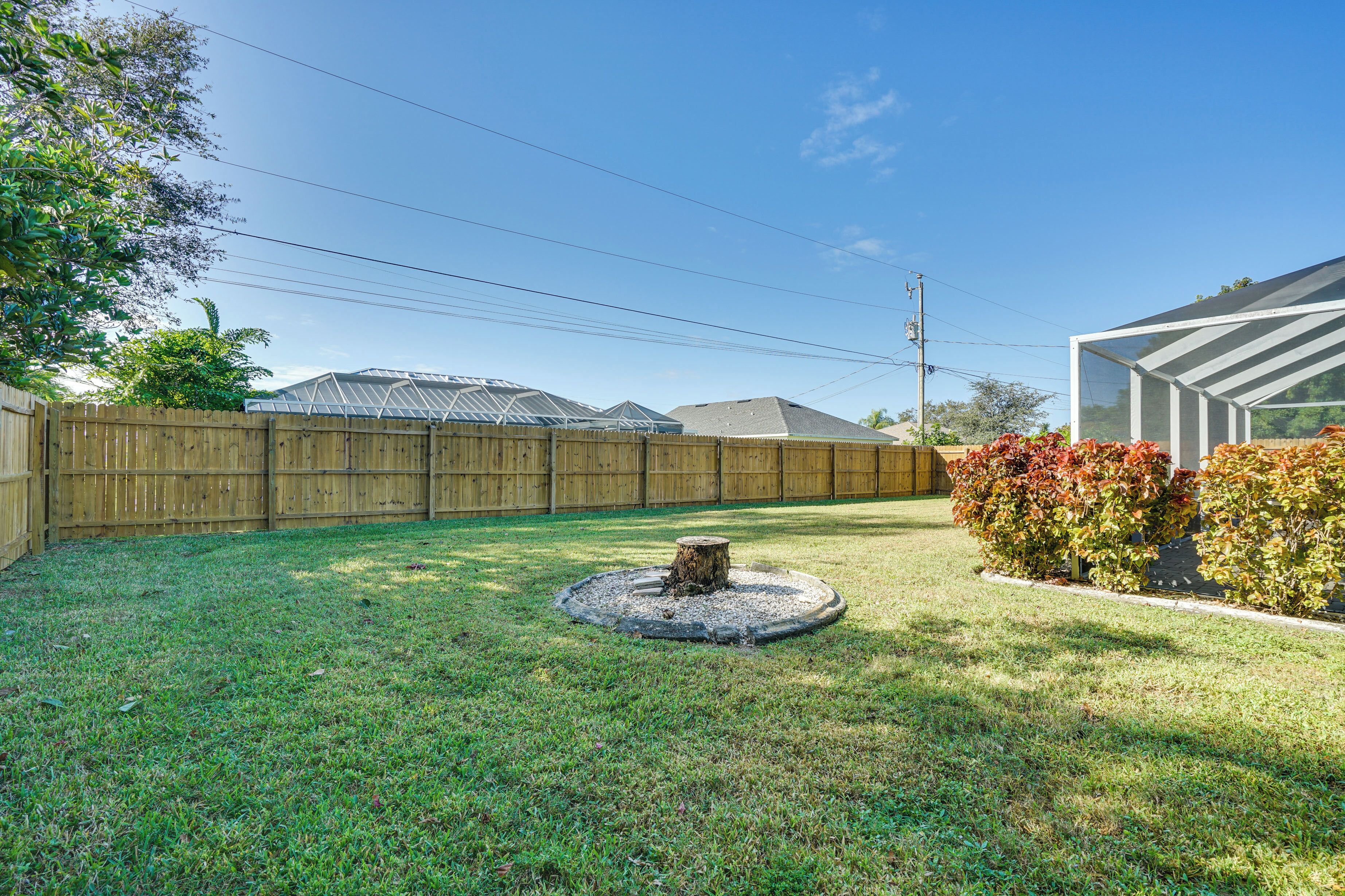 A backyard with a wooden fence, a circular garden feature, and a greenhouse structure.