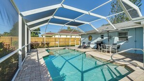 A covered outdoor swimming pool with a geometric roof structure, a patio area with lounge chairs, and a view of a residential building in the background. - 7 Mi to Beaches: Pet-friendly Cape Coral Home (Cape Coral)