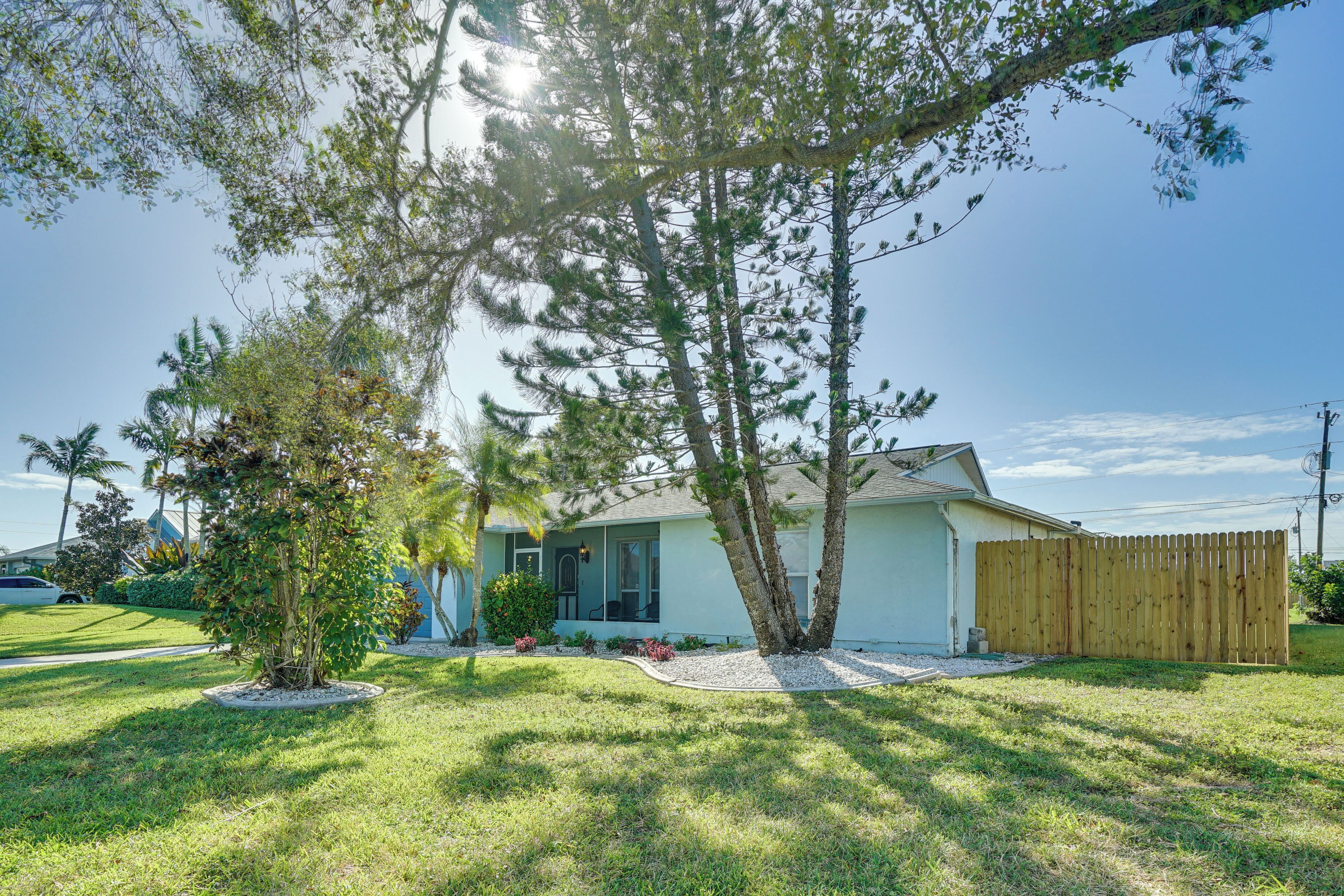 A residential house with a front yard, a wooden fence, and a small tree.