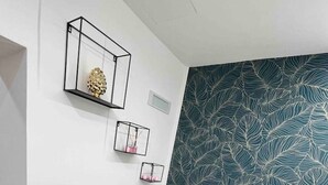 A dining area with a table set for two, a chair, and a wall with a leaf pattern. - CaBi's Dreams (Napoli)