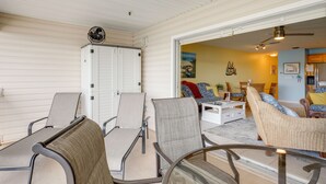 Une véranda avec une table en verre, des chaises et un ventilateur de plafond.