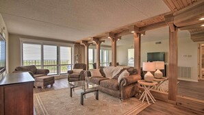 A spacious living room with a large window, a sofa set, a coffee table, and a wooden ceiling. - Welcoming Brigantine Condo w/ Ocean Views! (Brigantine)