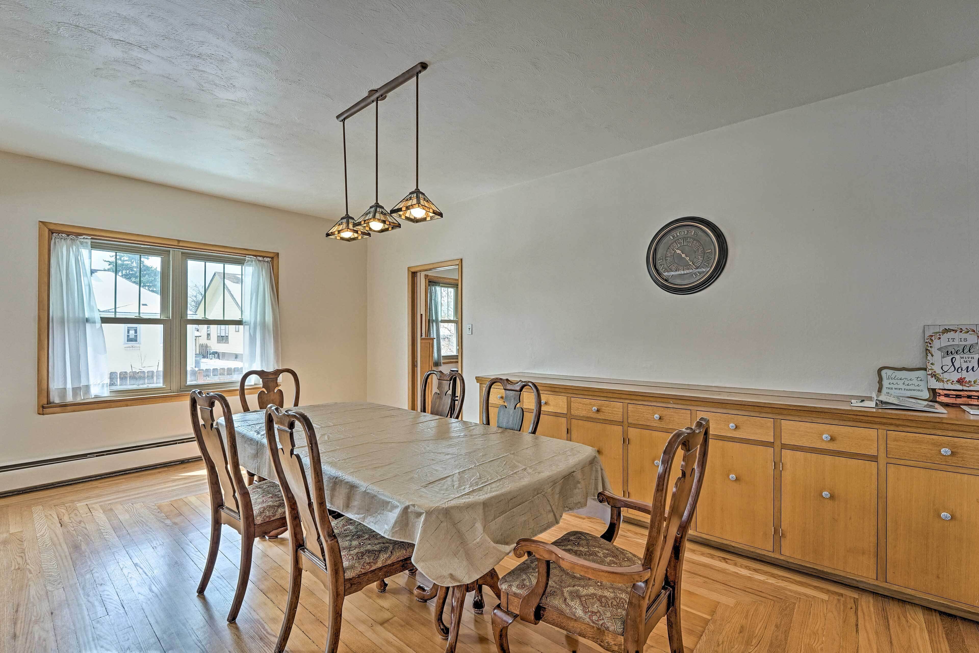 A dining area with a table, chairs, and a hanging light fixture.