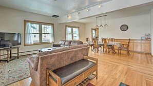 A spacious living room with a sofa, a TV, and a dining area with wooden furniture. - Laramie Home w/ Backyard < 1 Mi to Univ of Wyoming (Laramie)