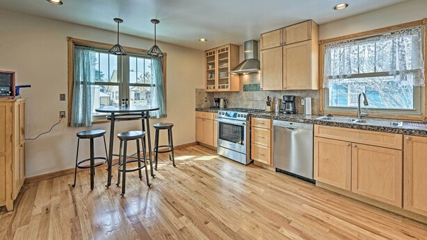 A modern kitchen with wooden cabinets, a built-in oven, a dishwasher, and a window with a view of the outside. - Laramie Home w/ Backyard < 1 Mi to Univ of Wyoming (Laramie)