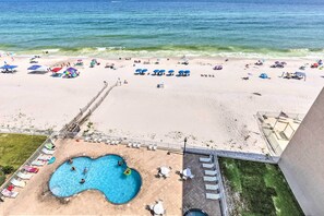 A beach with a swimming pool and lounge chairs. - Beachfront Condo With Balconies & Pool Access! (Gulf Shores)