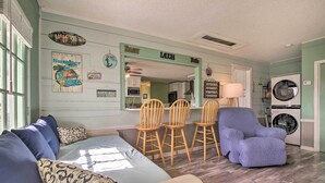 A living room with a sofa, chairs, and a blue armchair. There is a dining area with a table and chairs. A washing machine is visible in the background. - Pet-friendly Lake Buchanan Retreat w/ Fire Pit! (Tow)