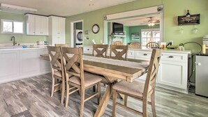 A dining area with a wooden table and chairs, a kitchen with white cabinets, a clock, and a sign on the wall. - Pet-friendly Lake Buchanan Retreat w/ Fire Pit! (Tow)