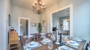 A dining room with a wooden table set for six, a chandelier, and a mirror reflecting the room. - Spacious Abode, Walk to Texas Heroes Square! (Gonzales)