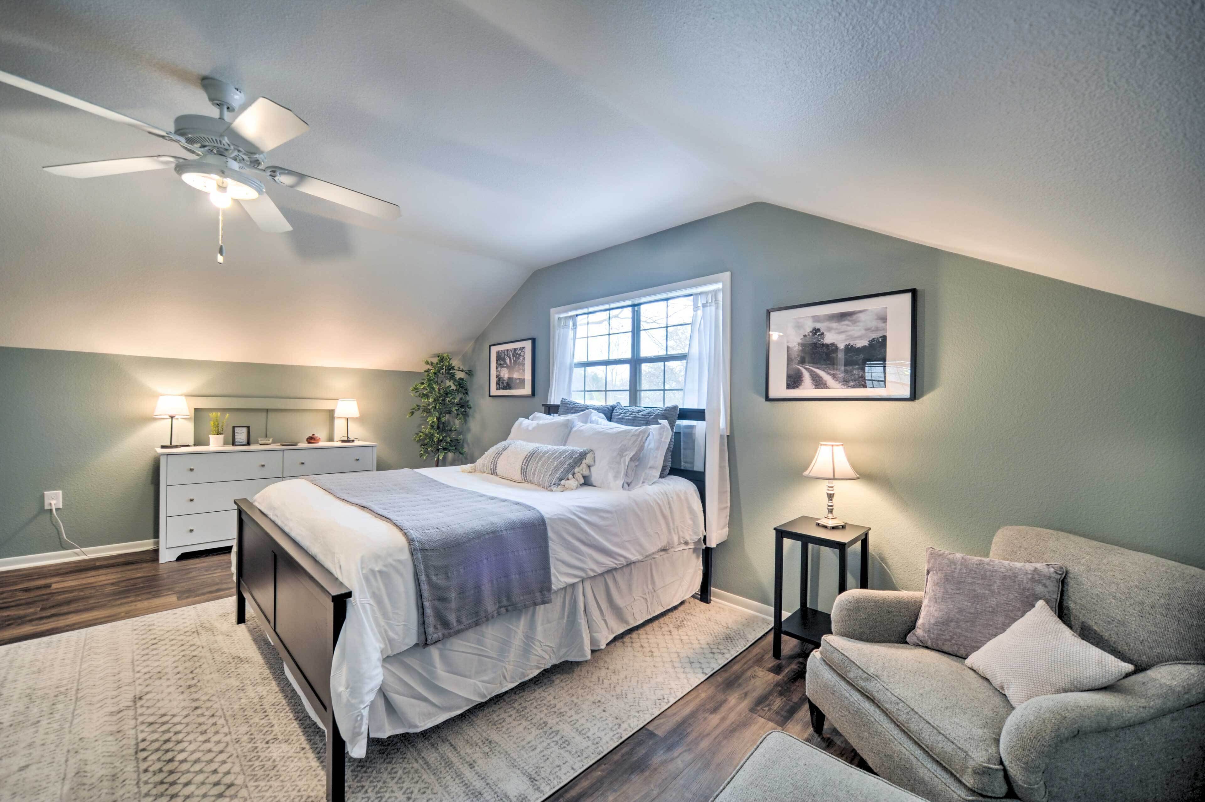 A bedroom with a bed, bedside tables, a ceiling fan, a window, and a couch.