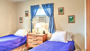 Een slaapkamer met twee bedden, een dressoir, een lamp en foto's in lijsten aan de muur.