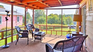 A covered patio with wicker furniture, a table, and a lamp. - Mayfield Home w/ Private Dock on Lake Sacandaga! (Mayfield)