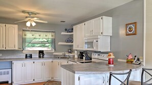 A kitchen with white cabinets, a microwave, a stove, and a ceiling fan. - Mayfield Home w/ Private Dock on Lake Sacandaga! (Mayfield)