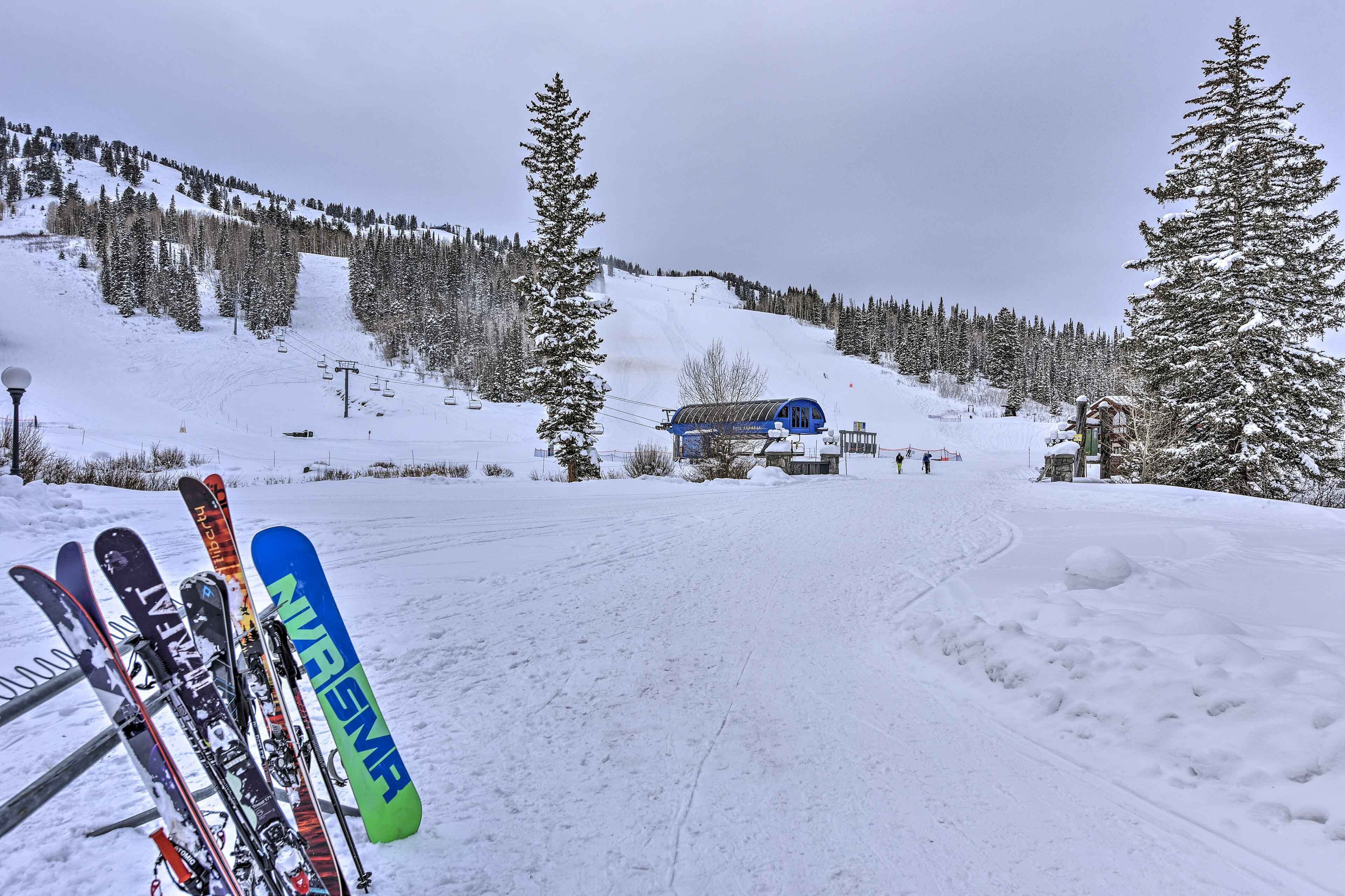 A snowy ski slope with a ski lift and a building in the background.