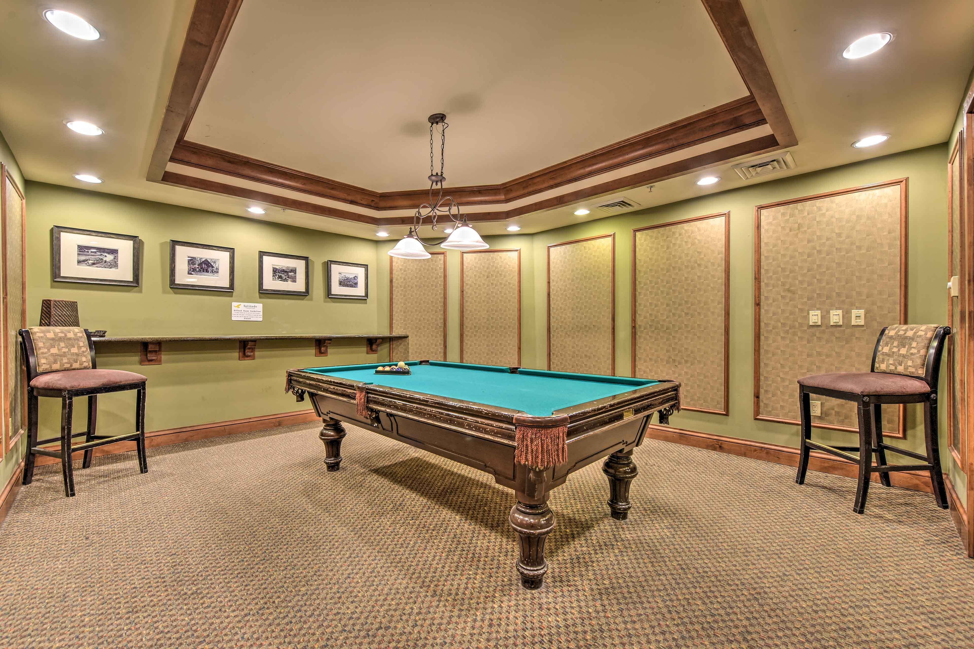 Une table de billard avec des chaises, des tableaux encadrés accrochés au mur et un plafond doté d’un éclairage encastré.
