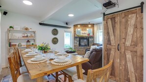 A dining area with a wooden table set for six, surrounded by chairs. A fireplace with a mirror above it is visible in the background. - Farmhouse w/ Private Hot Tub < 1 Mile to Birch Bay (Blaine)