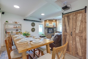 A dining area with a wooden table set for six, surrounded by chairs. A fireplace with a mirror above it is visible in the background. - Farmhouse w/ Private Hot Tub < 1 Mile to Birch Bay (Blaine)