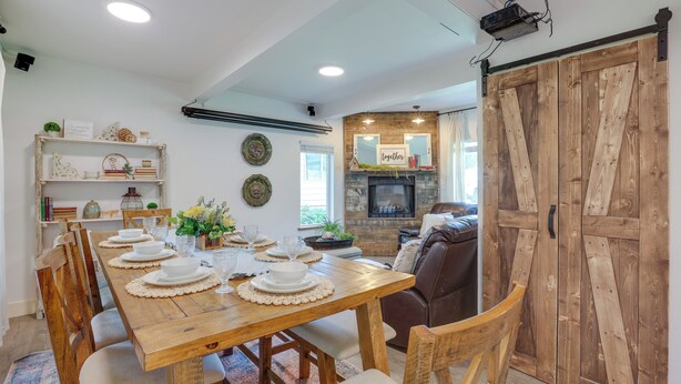 A dining area with a wooden table set for six, surrounded by chairs. A fireplace with a mirror above it is visible in the background. - Farmhouse w/ Private Hot Tub < 1 Mile to Birch Bay (Blaine)