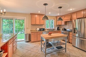 A modern kitchen with wooden cabinets, stainless steel appliances, and a large island. - Lakefront Homer Abode w/ Patio & Backyard! (Homer)