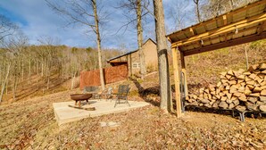 A rustic outdoor area with a wooden deck, a fire pit, and a covered seating area. - Cozy Waverly Cabin w/ Fireplace & Deck! (Waverly)