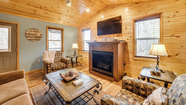 A cozy living room with a fireplace, wooden walls, and a ceiling fan. - Cozy Waverly Cabin w/ Fireplace & Deck! (Waverly)