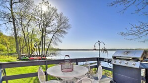 A deck with outdoor furniture, a grill, and a view of a lake. - Hilltop Green Lake Home: Dock, Kayaks, Views! (Princeton)