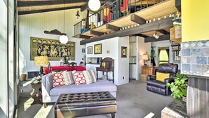 A spacious living room with a grey sofa, a black leather chair, and a fireplace. There is a wooden staircase with a red railing leading to an upper level. - Hilltop Green Lake Home: Dock, Kayaks, Views! (Princeton)