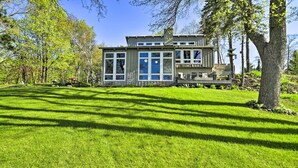 A modern house with large windows, a deck, and a well-maintained lawn. - Hilltop Green Lake Home: Dock, Kayaks, Views! (Princeton)