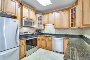 A kitchen with wooden cabinets, stainless steel appliances, and a granite countertop. - Gulf Coast Luxury Getaway on Orange Beach w/ Views (Orange Beach)
