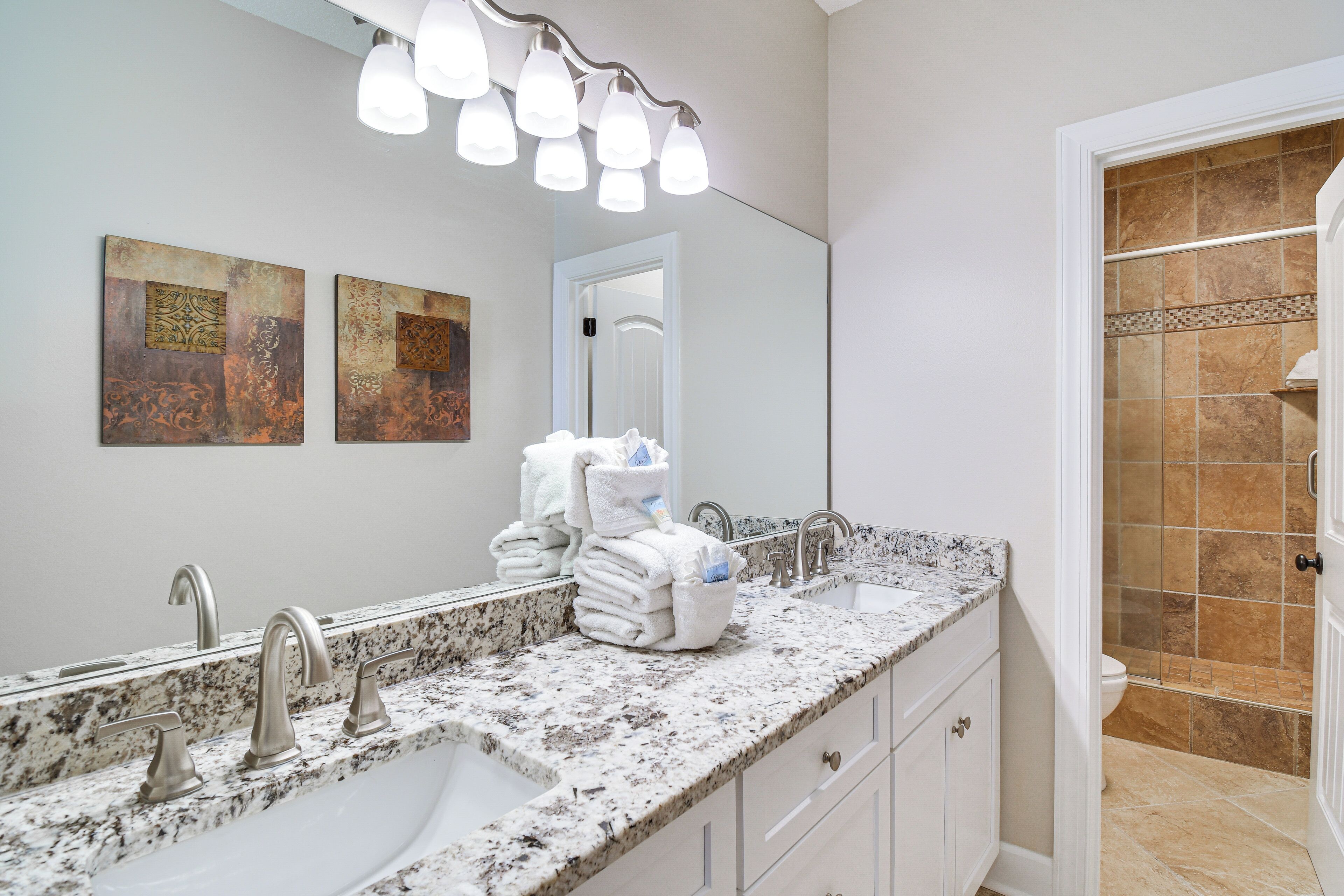 A bathroom with a double sink, a mirror, and a shower area.