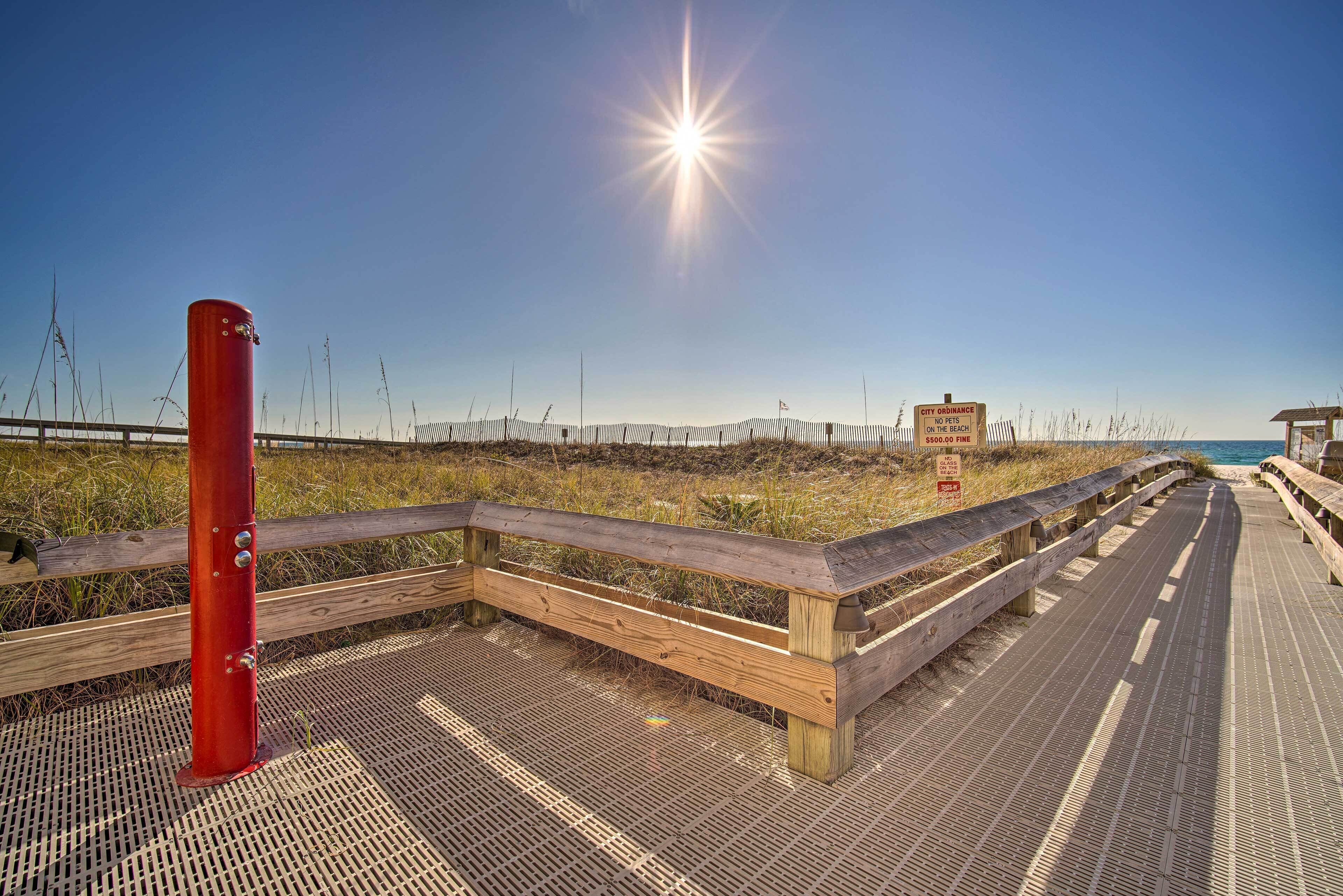A wooden boardwalk leading to a beach with a red pole and a sign indicating a city ordinance on the beach.