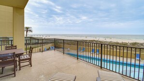 Balcón con piscina, vista a la playa y mobiliario exterior.