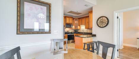 A modern kitchen with wooden cabinets, a stainless steel refrigerator, and a central island with stools.
