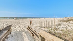 Una playa arenosa con pasarelas de madera y sombrillas azules.