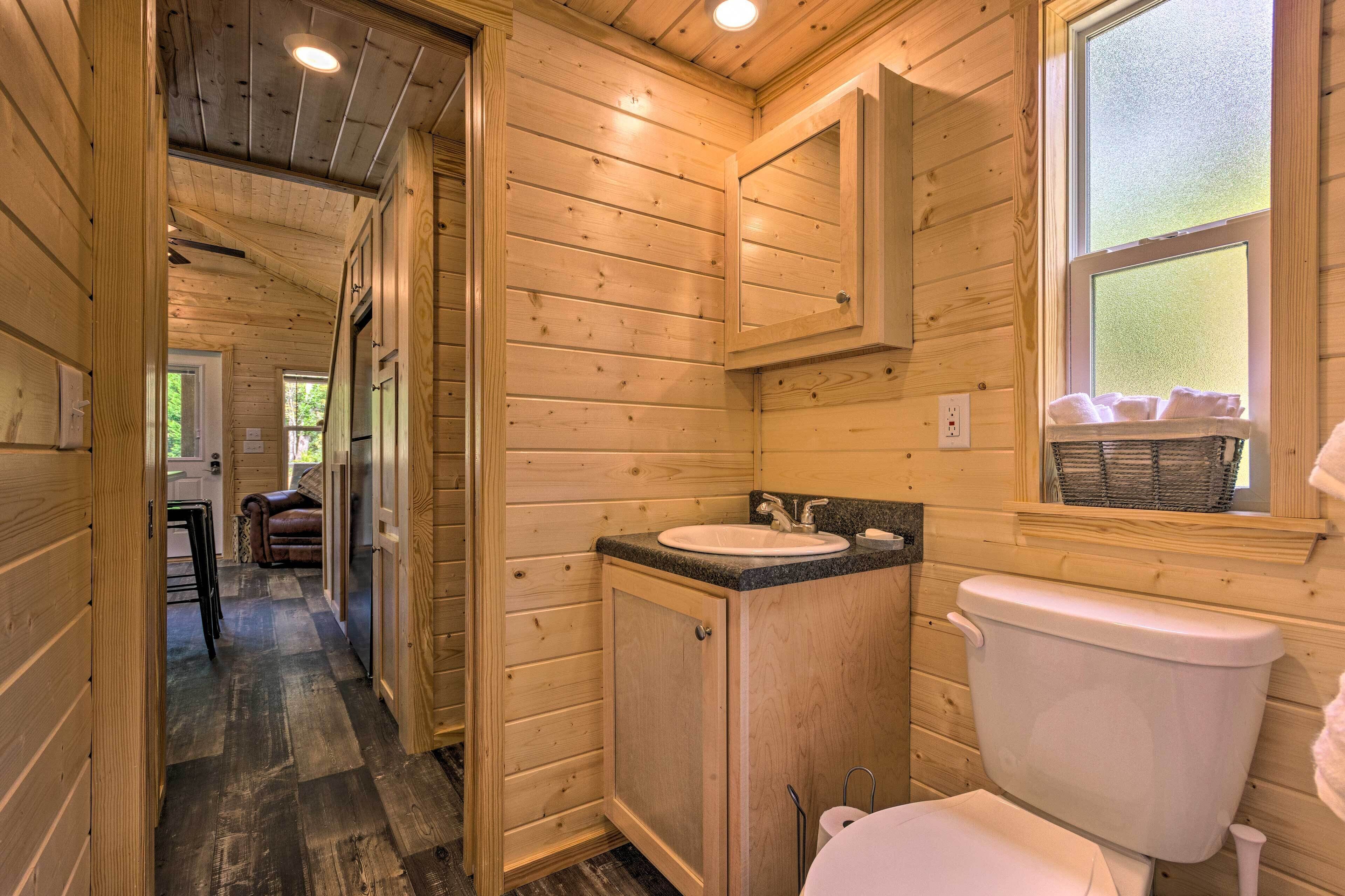 Une salle de bain rustique, aménagée dans une cabane en bois, avec un lavabo, des toilettes et une fenêtre.