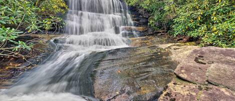 Une cascade d’eau qui dévale des rochers dans une zone boisée.