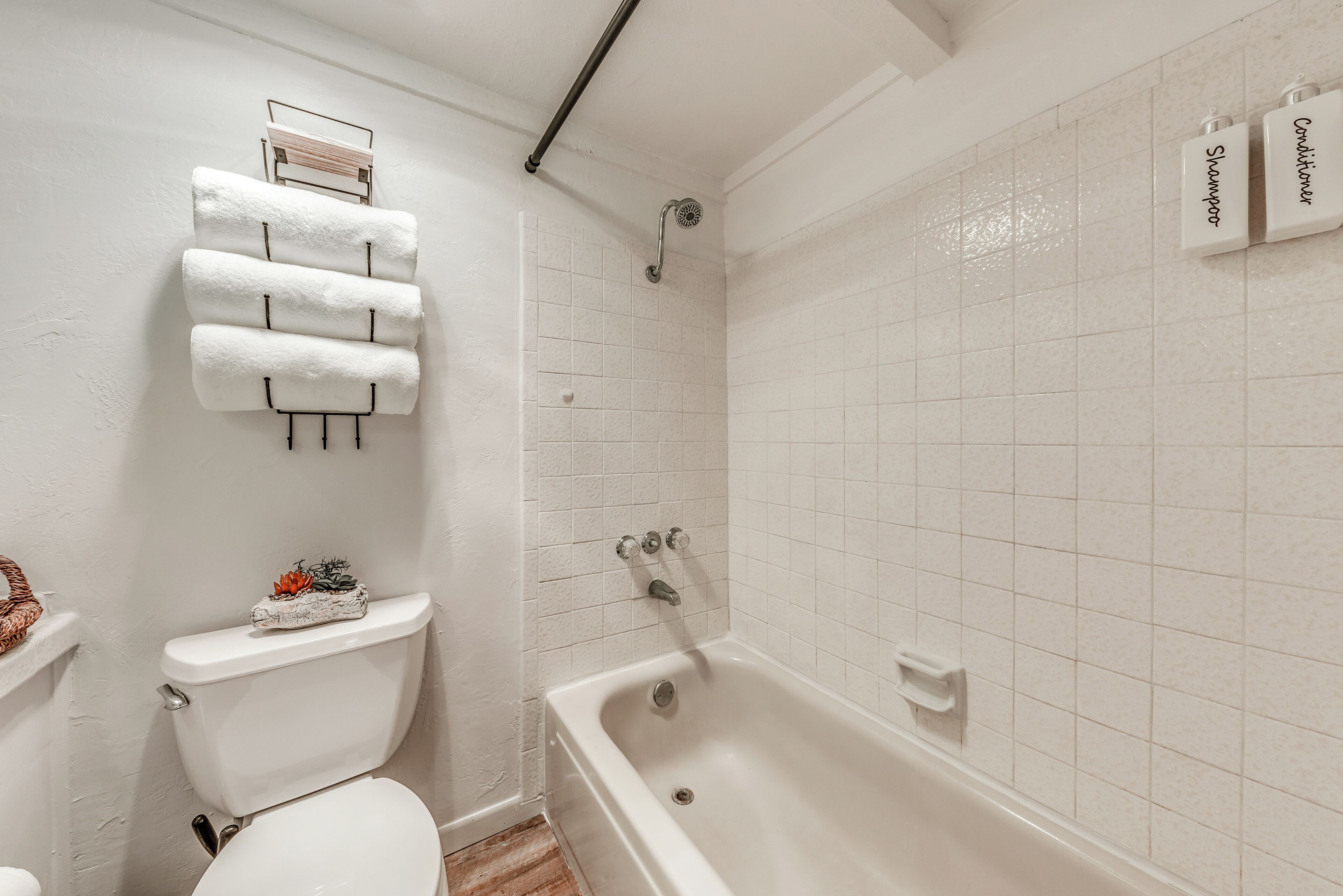 A bathroom with a toilet, a bathtub, and a shower. There are towels hanging on a rack.