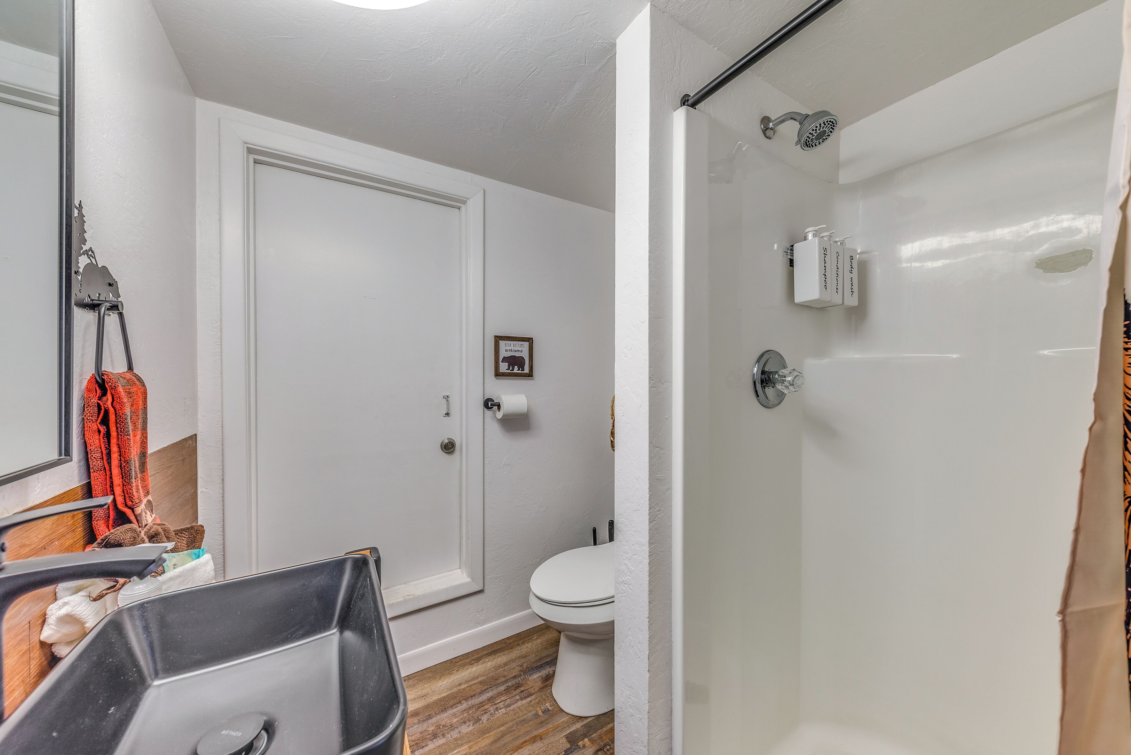 Een badkamer met een douche, toilet en wastafel.