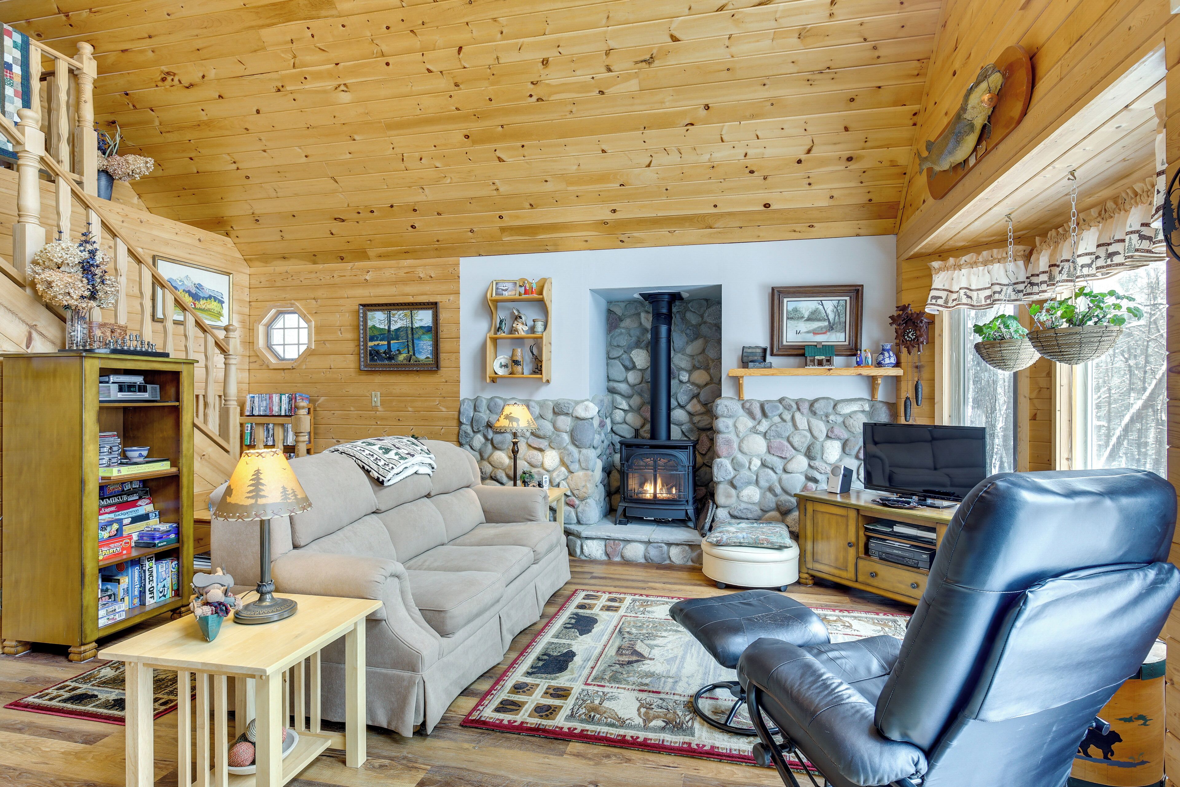 Een knusse woonkamer met een stenen open haard, houten plafond en een leren fauteuil.