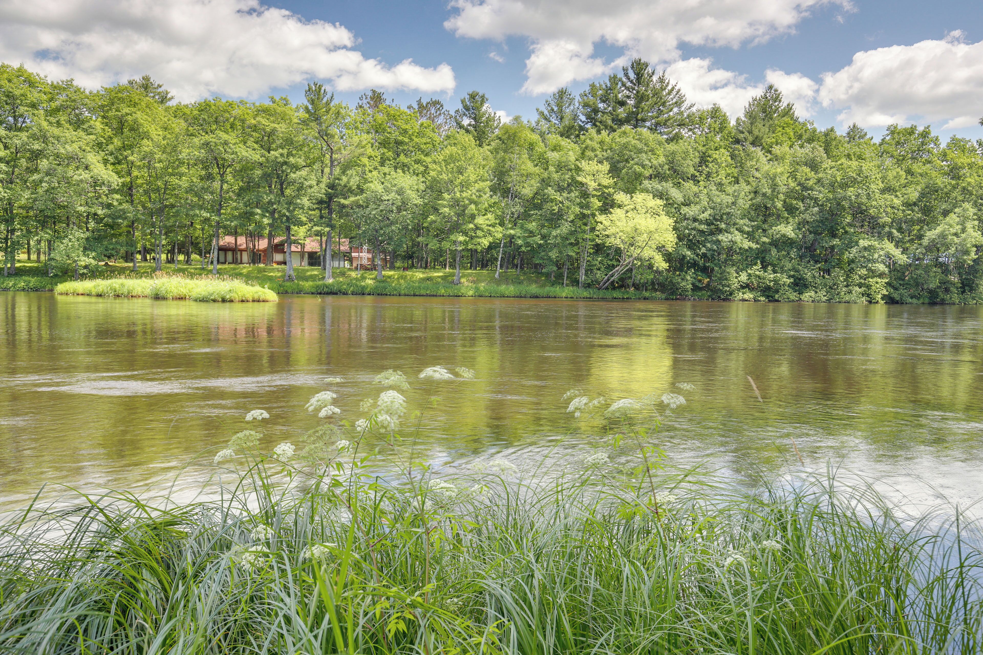 Una vista tranquilla su un lago, con una casa circondata da vegetazione lussureggiante e alberi.