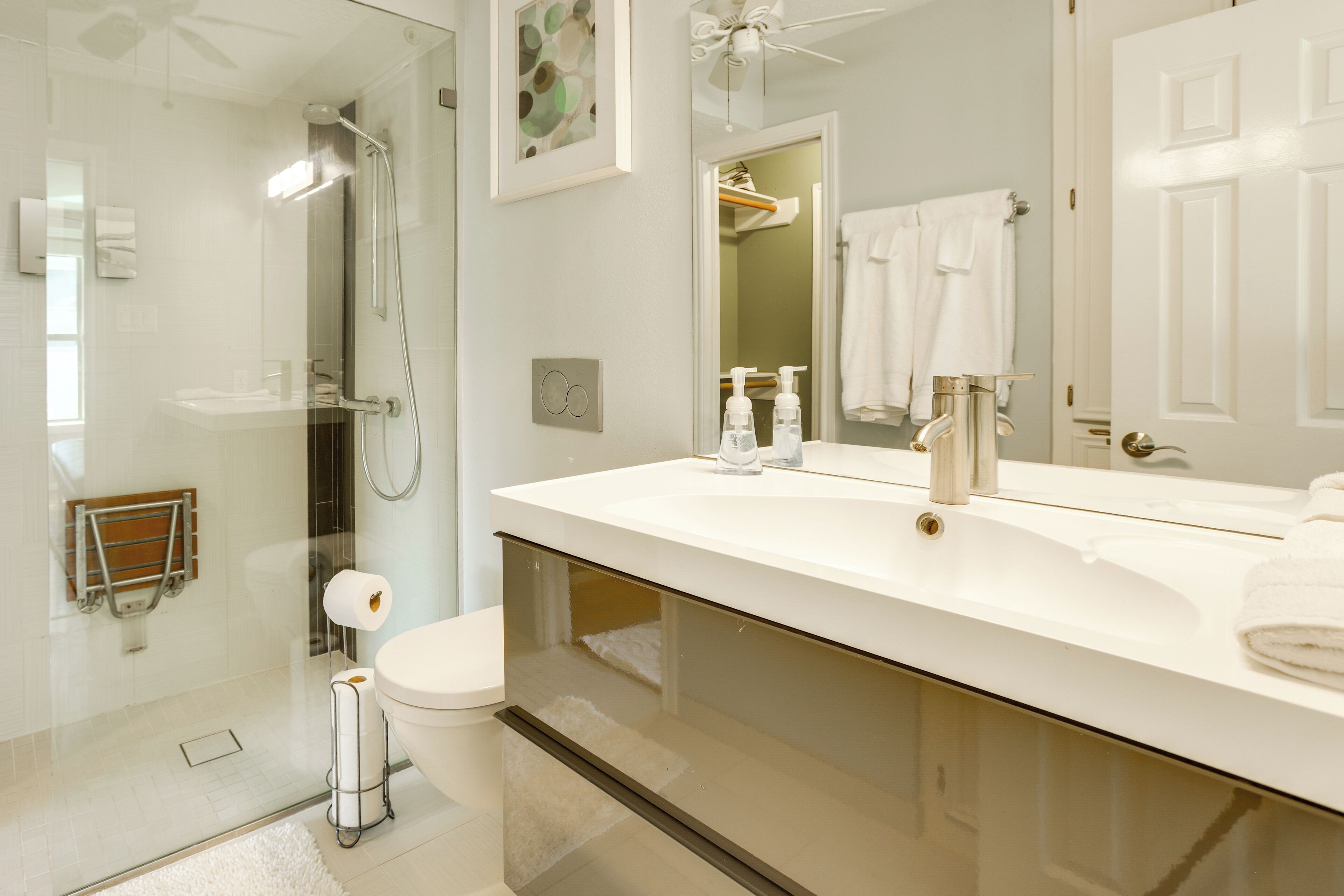 A modern bathroom with a glass-enclosed shower, a white sink, and a large mirror.