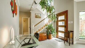A modern office space with a glass desk, a potted plant, and a staircase.