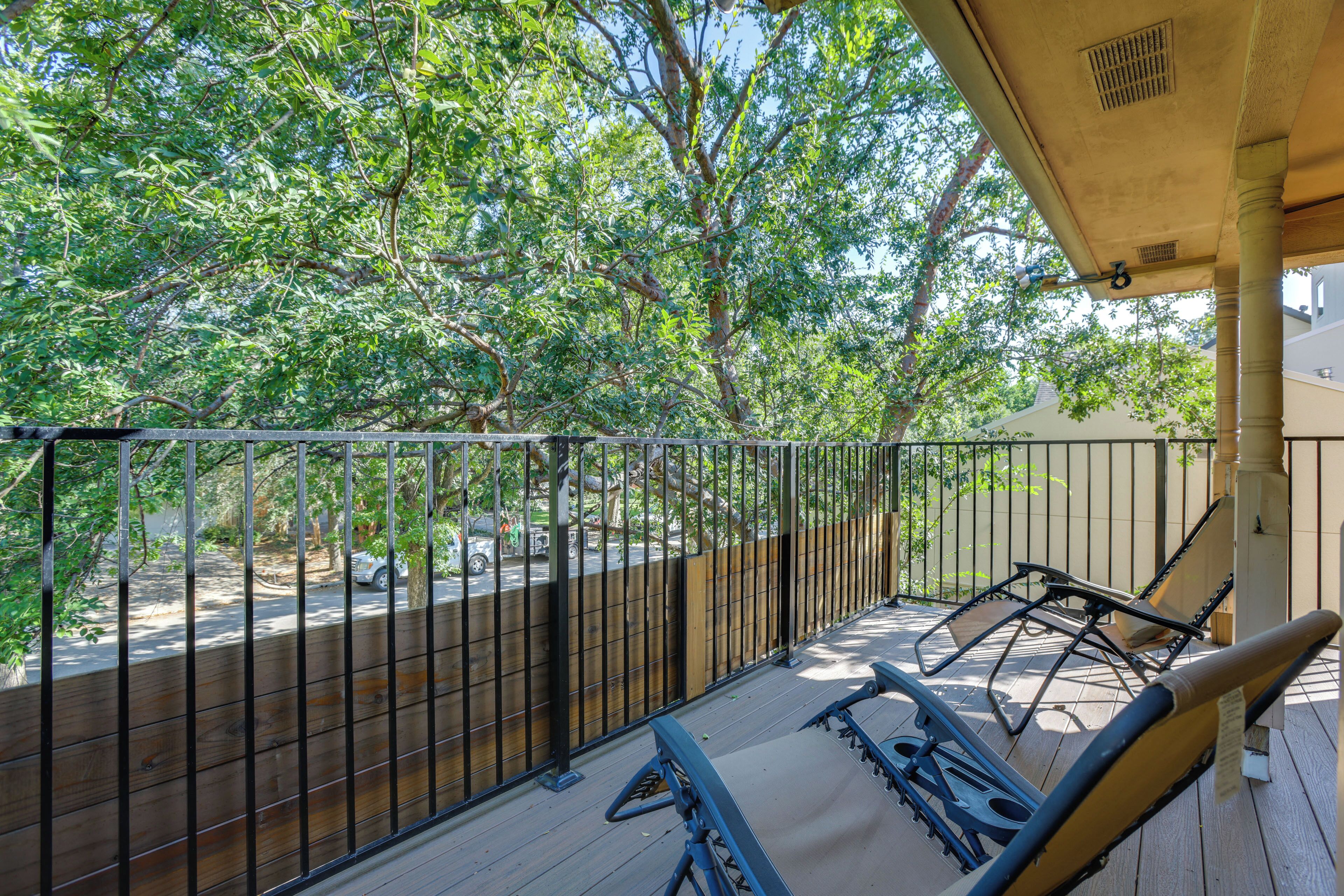 A balcony with a view of trees and a fence.